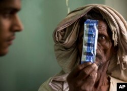 FILE - A tuberculosis patient holds medicines at the Lal Bahadur Shastri Government Hospital at Ram Nagar in Varanasi, India, March 13, 2018.