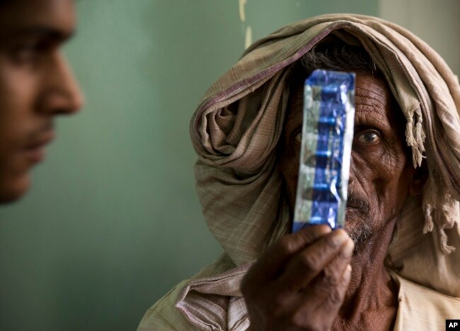 FILE - A tuberculosis patient holds medicines at the Lal Bahadur Shastri Government Hospital at Ram Nagar in Varanasi, India, March 13, 2018.