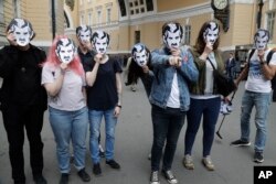 FILE - People wear face masks depicting the Big Brother character from George Orwell's novel 1984, as they attend a protest rally in support of greater Internet freedom, in St.Petersburg, Russia, July 16, 2017.