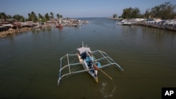 FILE - In this May 7, 2013 photo, a fishing boat returns to their village in the coastal town of Masinloc, Zambales province, northwestern Philippines. 