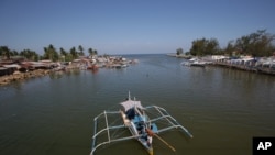 FILE - In this May 7, 2013 photo, a fishing boat returns to their village in the coastal town of Masinloc, Zambales province, northwestern Philippines.