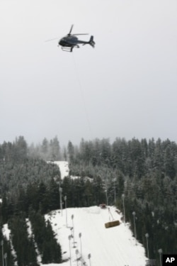Warm temperatures forced organizers to truck and airlift snow to the venue. Here, hay is dropped on Cypress Mountain, scene of freestyle skiing and snowboarding events.