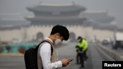 A student wearing a mask uses his mobile phone during a polluted day in Seoul, South Korea, March 5, 2019. 