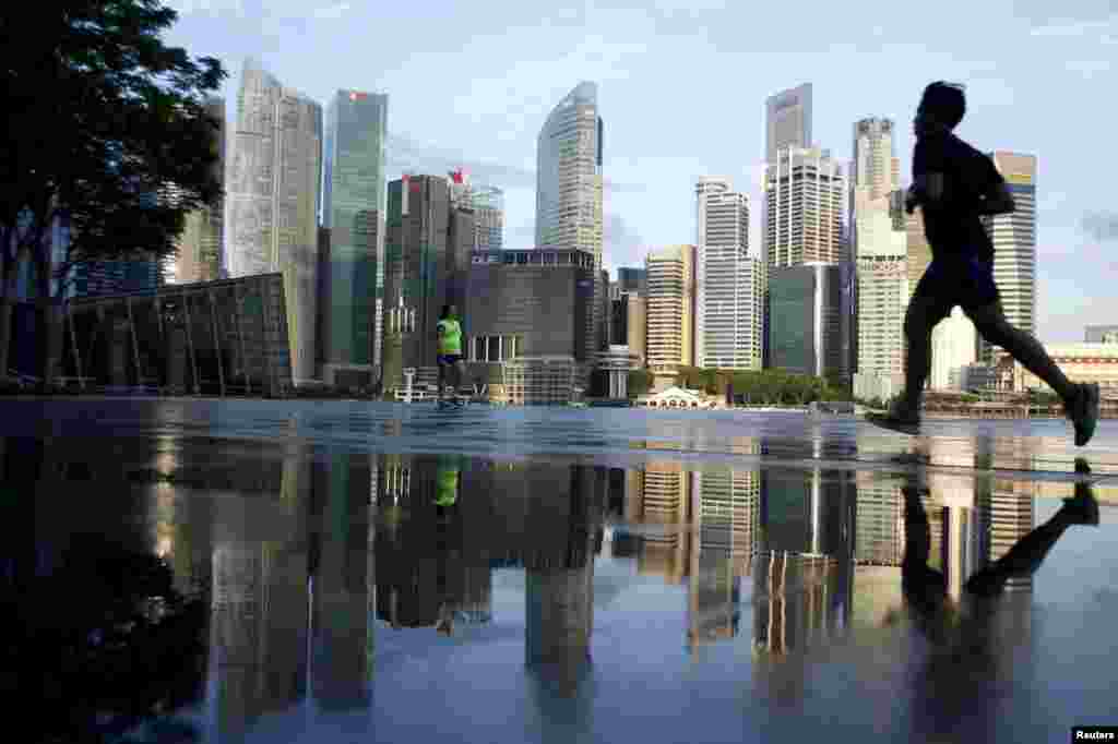 Joggers pass the skyline of the central business district in Singapore.