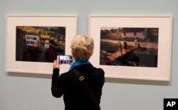 In this March 15, 2018, photo, a woman views a pair of Paul Fusco photographs that are part of the exhibit, "The Train: RFK's Last Journey," at the San Francisco Museum of Modern Art in San Francisco.