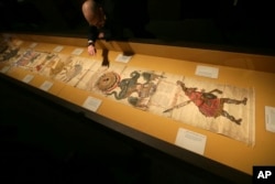 A member of British Library staff poses for a picture pointing at the Philosopher's Stone on the 16th-century Ripley Scroll, which describes how to make a Philosopher's Stone, at the "Harry Potter - A History of Magic" exhibition at the British Library, i