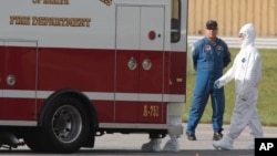 Un médico estadounidense expuesto al virus del ébola llega caminando a una ambulancia en el aeropuerto de Frederick, al norte de Maryland.