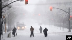 Les gens marchent sur une route couverte de neige pendant la tempête de neige, à Jersey City, NJ, 23 janvier 2016.