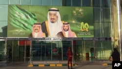 FILE - Images of King Salman, center, Crown Prince Mohammed bin Nayef, left, and Deputy Crown Prince Mohammed bin Salman hang at the entrance of a shopping center in Riyadh, Saudi Arabia, Dec. 14, 2015. 