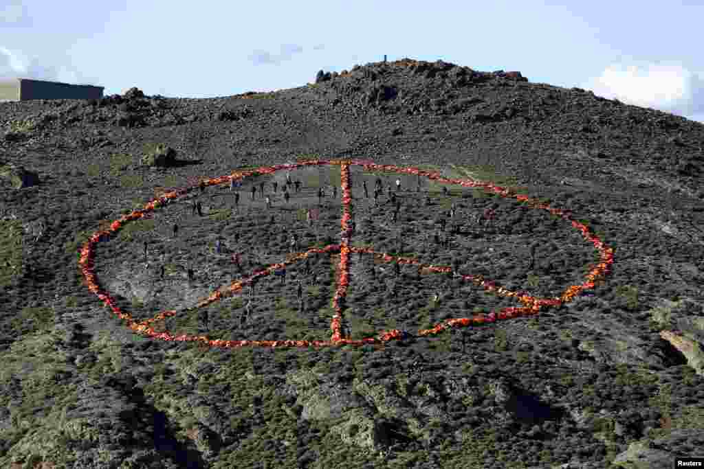 Volunteers from non-governmental organizations (NGO) arrange more than 2,500 discarded lifejackets, used by refugees and migrants, in the shape of the peace symbol on the Greek island of Lesbos.