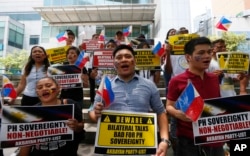 FILE - Protesters shout slogans and display placards outside of the Chinese Consulate in protest of China's occupation and island-building in the disputed Spratly Island group in the South China Sea in Makati city's financial district east of Manila, Philippines.