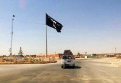 FILE - A motorist passes by a flag of the Islamic State group in central Rawah, 175 miles (281 kilometers) northwest of Baghdad, Iraq, July 22, 2014.