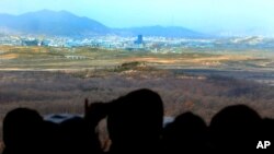 Visitors look at the industrial complex in Kaesong, North Korea, through binoculars at Dora Observation Post in the demilitarized zone (DMZ) near the border village of Panmunjom, in Paju, South Korea, April 9, 2013. 