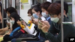 Passengers wear masks as a precaution against Middle East Respiratory Syndrome (MERS) as they use their smartphones on a subway train in Seoul, South Korea, June 8, 2015. 