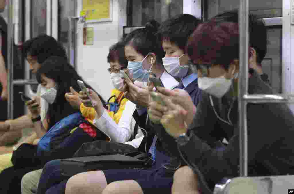 Para penumpang mengenakan masker untuk berjaga-jaga agar tidak tertular Middle East Respiratory Syndrome (MERS) sambil mengakses smartphone mereka di kereta bawah tanah di Seoul, Korea Selatan.
