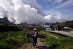 Seorang warga desa membawa kayu untuk memasak di dekat proyek Pembangkit Listrik Tenaga Panas Bumi (PLTP) Dipa Energi di daerah pegunungan Dieng, provinsi Jawa Tengah 3 Oktober 2010. (Foto: Reuters/Beawiharta)