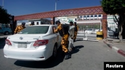 Police troopers check a car at the gate of a hospital where a Japanese diplomat is being treated in Sana'a, Dec. 15, 2013. 