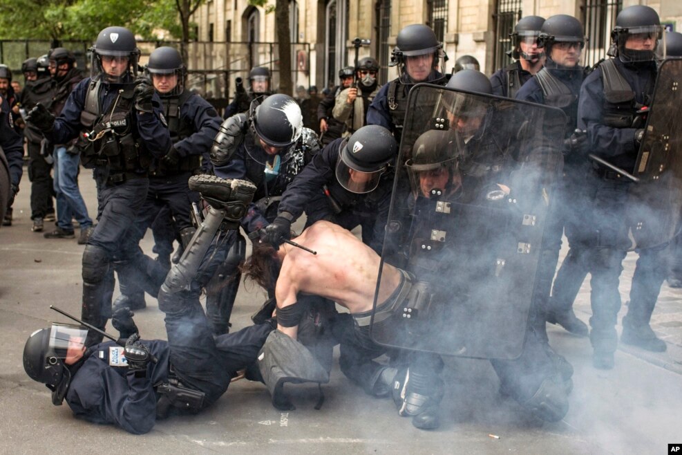 Riot police officers detain a man during a demonstration against a labor law bill in Paris, France.