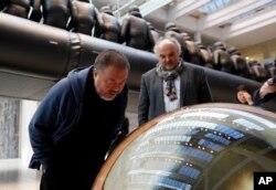 Chinese activist and artist Ai Weiwei looks into a glass ball which is part of his installation at the National Gallery in Prague, Czech Republic, March 16, 2017.