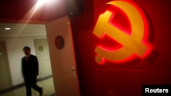 A trainee walks pass a communist party logo as he attends a training course at the communist party school called China Executive Leadership Academy, Sept. 2012.