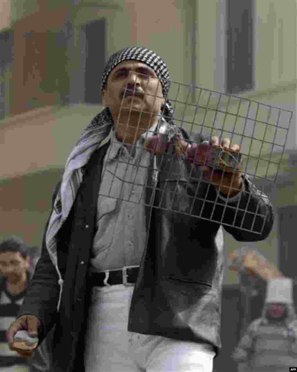 An anti government protestor holds stones and a grille shield during clashes in Cairo, Egypt, Thursday, Feb. 3, 2011. Another bout of heavy gunfire and clashes erupted Thursday around dusk in the Cairo square at the center of Egypt's anti-government chaos