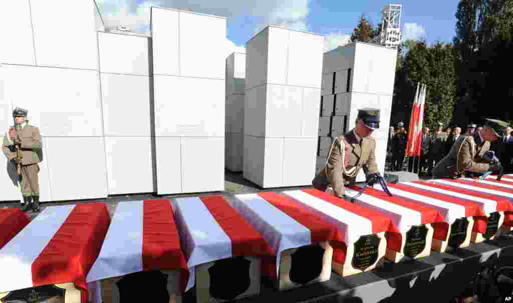 Polish Army soldiers adjust ribbons on coffins during the first burials of World War II heroes who were later secretly slain by the communists, at the Powazki cemetery in Warsaw, Poland. Remains of 35 Polish soldiers with bullet holes through the back of the skull were burried after being recently recovered from unmarked mass graves.