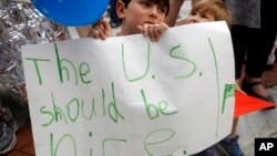Shua Rich, age 6, holds his sign as he protests with his mother during a rally against U.S. immigration policies outside an office for Rep. Kevin Yoder, June 22, 2018, in Overland Park, Kan.