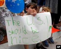Shua Rich, age 6, holds his sign as he protests with his mother during a rally against U.S. immigration policies outside an office for Rep. Kevin Yoder, June 22, 2018, in Overland Park, Kan.