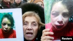 A protester holds pictures of journalist Tetyana Chornovil, who was beaten after publishing an article on the assets of top government officials Dec. 26 2013 (Reuters) 