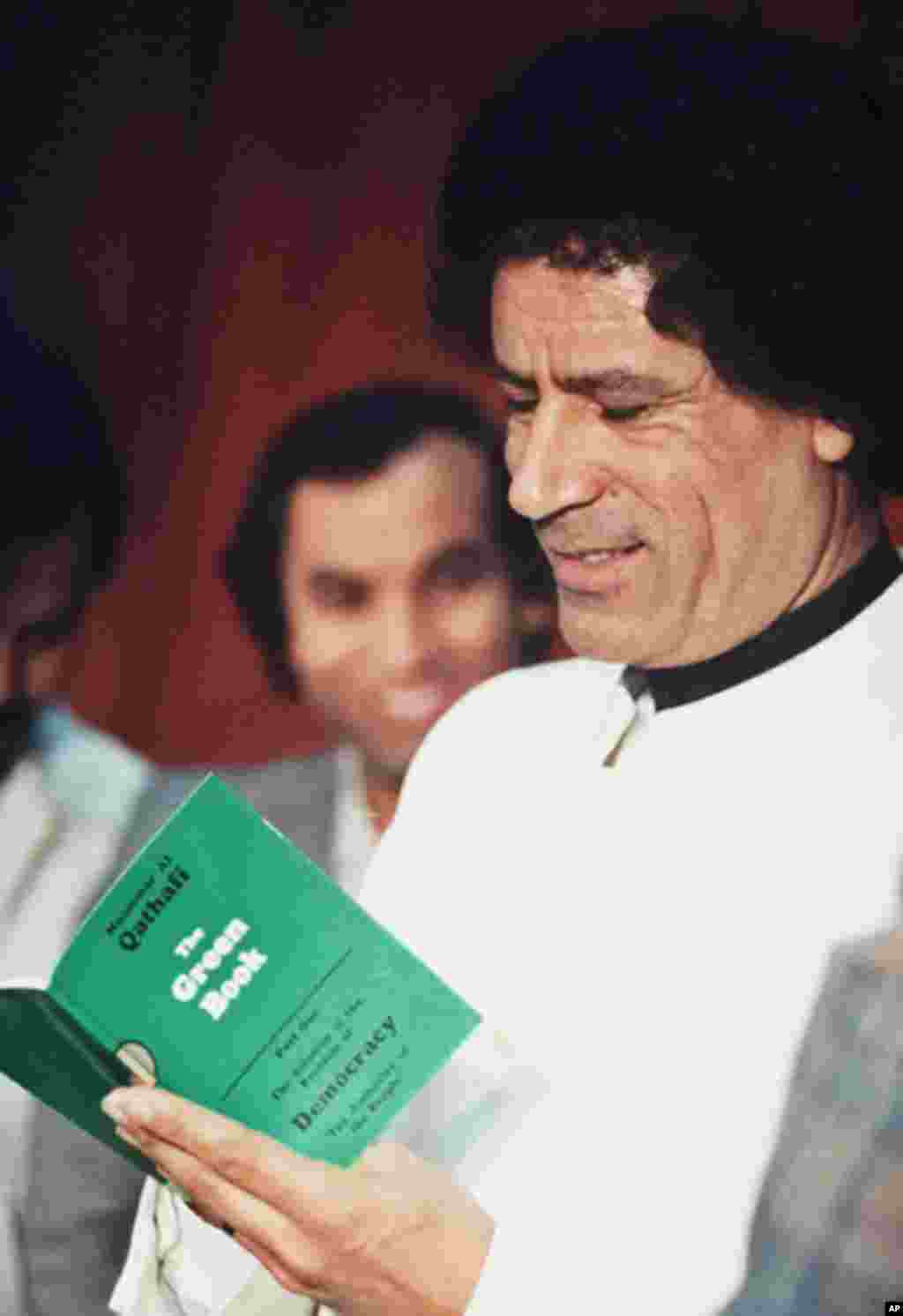 File picture of Libyan leader Moammar Gadhafi reading his green book in Libya, 05 January 1984, (AFP).