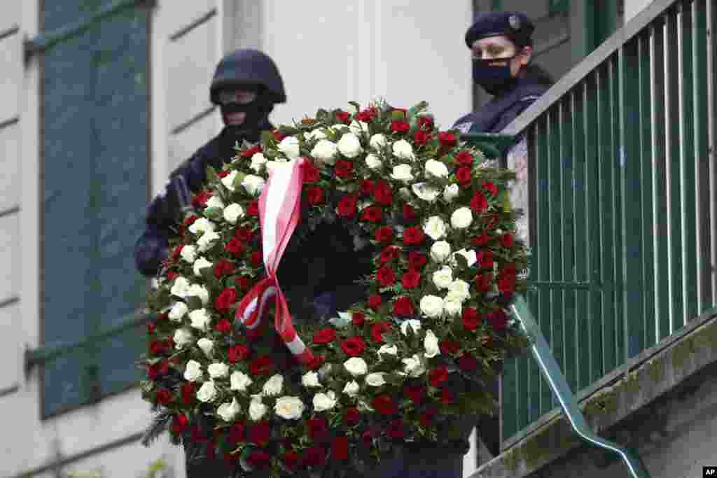 A man carries a wreath as he walks past police officers in Vienna, Austria. A deadly rampage left four dead and at least 15 wounded in multiple locations in the city in what Austrian Chancellor Sebastian Kurz labeled a &ldquo;repulsive terror attack.&rdquo;&nbsp;&nbsp;