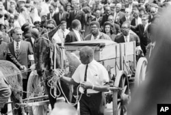 FILE - A mule cart carries Martin Luther King Jr.'s mahogany casket through the streets of Atlanta, April 10, 1968, en route to funeral services at Morehouse College.