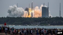 People watch a Long March 5B rocket, carrying China's Tianhe space station core module, as it lifts off from the Wenchang Space Launch Center in southern China's Hainan province on April 29, 2021. (Photo by STR / AFP) / China OUT