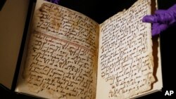 Seorang staf universitas menunjukkan halaman Al Quran tertua yang pernah ditemukan, di Universitas Birmingham, di kota Birmingham, Inggris (foto: AP).