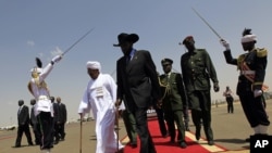 South Sudanese President Salva Kiir (C) walks with his Sudanese counterpart Omar al-Bashir (in white) before Kiir's departure from Khartoum, October 9, 2011. 