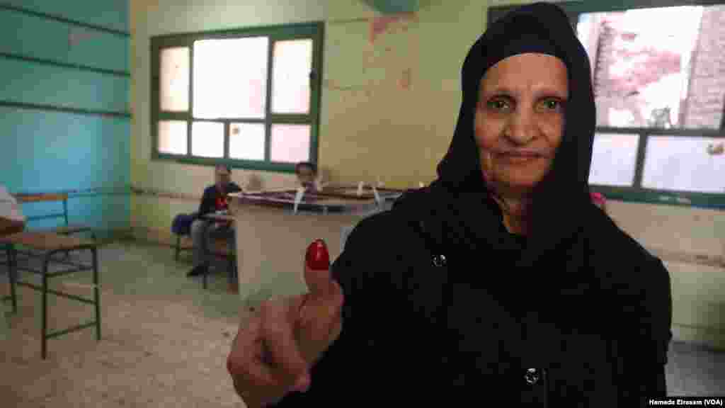 Seorang perempuan Mesir memamerkan jarinya yang bertinta setelah memberikan suara dalam pemilihan parlemen di tempat pemungutan suara di Safya Zaghlol di Giza, Mesir (18/10).