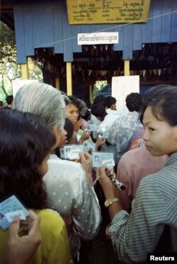 FILE - Cambodians hold their ID cards as they queue at a polling station in Phnom Penh July 26, 1998. Cambodians flocked to vote in crucial general elections after a campaign criticised by the opposition and human rights groups as unfair but given cautious approval by the international community.
