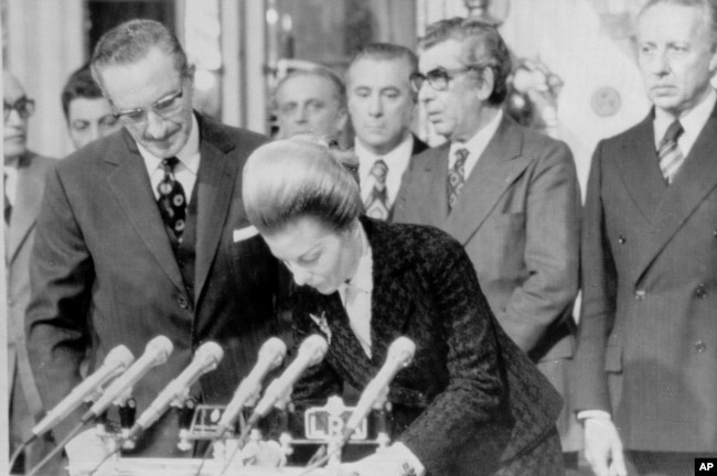 FILE - Then-Argentine President Isabel Peron signs government records after swearing in five new cabinet ministers in Buenos Aires, Argentina Aug. 11, 1975.