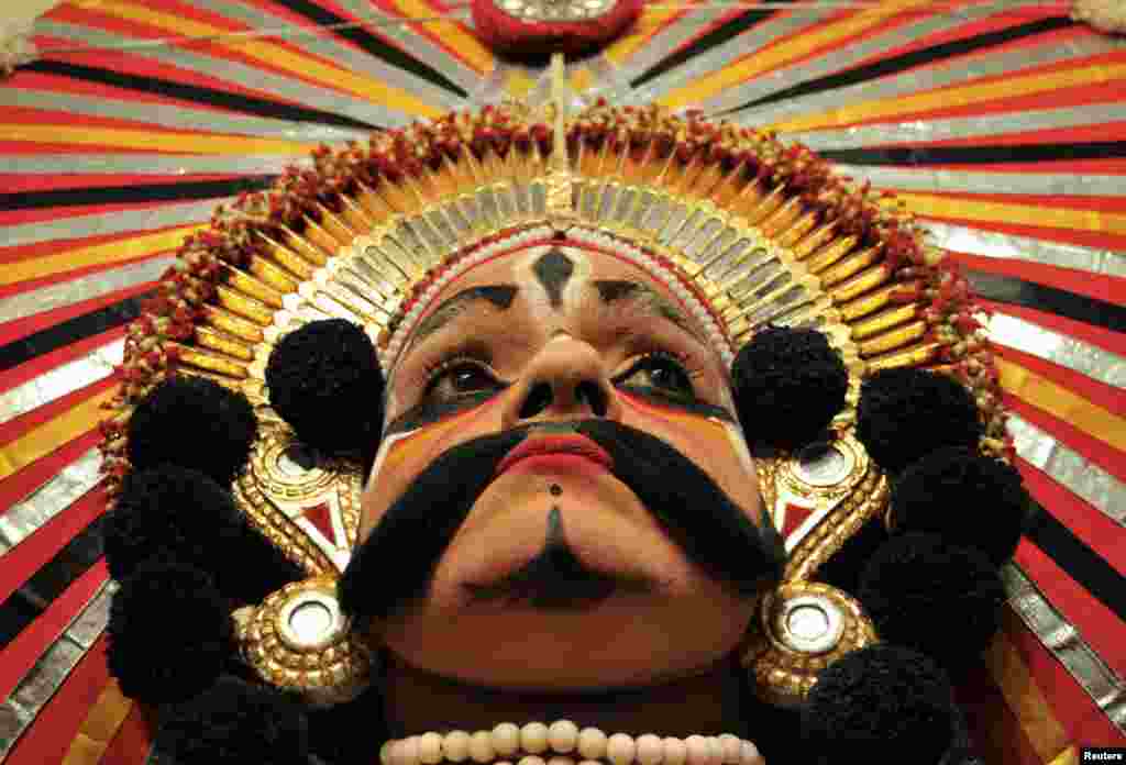 A folk artist wearing a traditional headdress waits backstage to perform during an event to mark the third anniversary of Yakshagana Kala Sangha, a traditional folk dance, in the southern Indian city of Bangalore. 