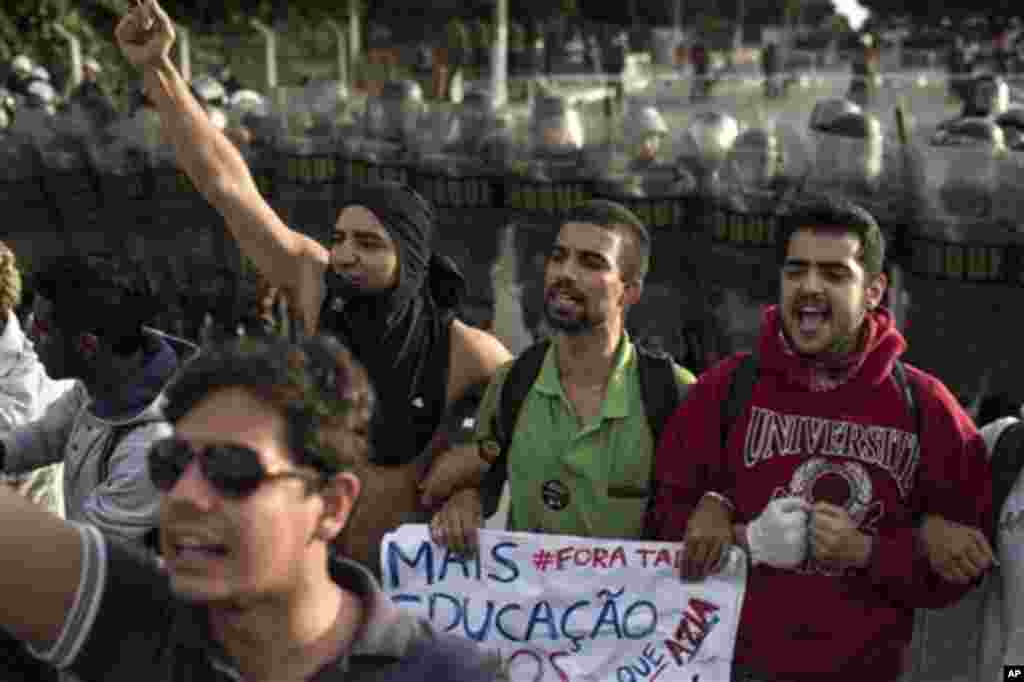 People shout slogans asking for no violence as a line of police stands behind them as they protest outside the Minerao stadium where a Confederations Cup soccer match takes place between Japan and Mexico in Belo Horizonte, Brazil, Saturday, June 22, 2013.