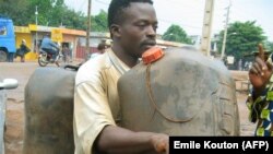 FILE: An illegal gasoline vendor fills a container 03 June 2006 in the town of Porto Novo, 30 km east of the capital, Cotonou.