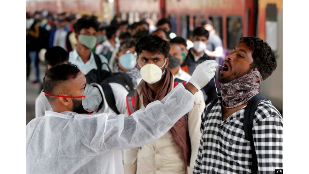 Seorang petugas kesehatan mengumpulkan sampel swab dari seorang pelancong di stasiun kereta api untuk menguji COVID-19 sebelum mengizinkannya memasuki kota itu, di Mumbai, India, Rabu, 12 Januari 2022. (Foto: AP/Rajanish kakade)