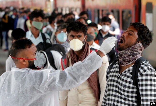 Seorang petugas kesehatan mengumpulkan sampel swab dari seorang pelancong di stasiun kereta api untuk menguji COVID-19 sebelum mengizinkannya memasuki kota itu, di Mumbai, India, Rabu, 12 Januari 2022. (Foto: AP/Rajanish kakade)