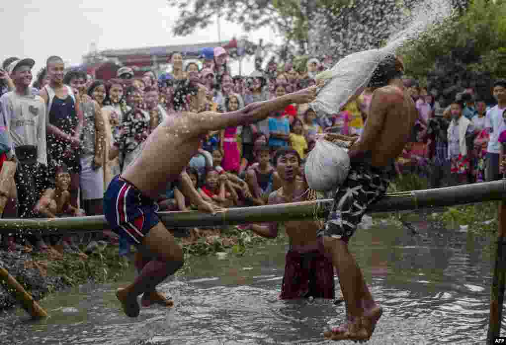 미얀마 양곤 외곽에서 열린 독립 70주년 축제에서 청년들이 대나무 기둥을 타고 전통 베개 싸움을 하고 있다.