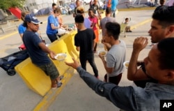 FILE - Migrants seeking asylum in the United States receive breakfast from a group of volunteers near the international bridge, April 30, 2019, in Matamoros, Mexico.