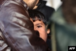 A man comforts a child as people mourn the death of members of the Palestinian Akasha family, killed in an Israeli strike on the Sheikh Adwan neighborhood north of Gaza City, at the al-Maamadani hospital on Nov. 30, 2024.