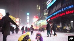 ພວກເດັກນ້ອຍ ພາກັນຫລິ້ນຫິມະ ທີ່ຈະຕຸລັດ Times Square ໃນລະຫວ່າງພາຍຸຫິມະ ເມື່ອວັນພະຫັດ ທີ 2 ມັງກອນ 2014.