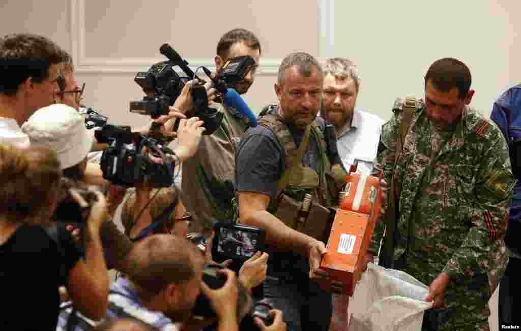 A pro-Russian separatist shows members of the media a black box belonging to Malaysia Airlines flight MH17 before its handing it over to Malaysian representatives in Donetsk, Ukraine.