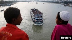 FILE - An overcrowded passenger boat navigates through Buriganga River as people watch from a bridge in Dhaka, Bangladesh, July 27, 2014.