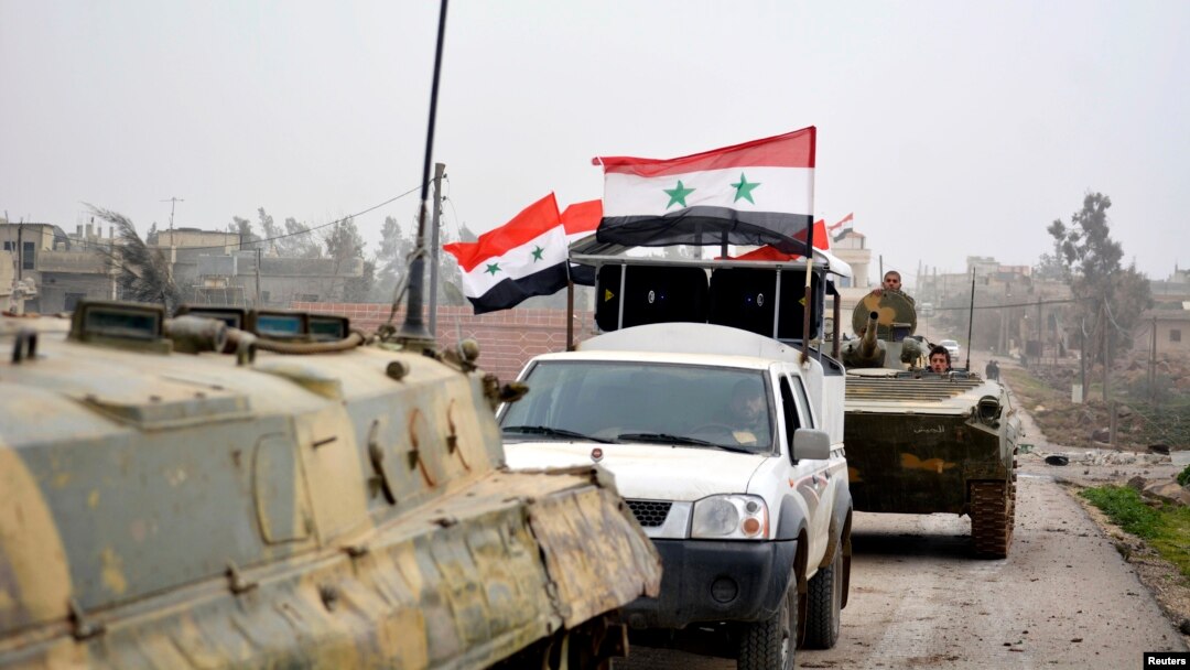 FILE - Fighters loyal to Syria's President Bashar Al-Assad ride on military vehicles and tanks after regaining control of Deir al-Adas, a town south of Damascus, Daraa countryside.